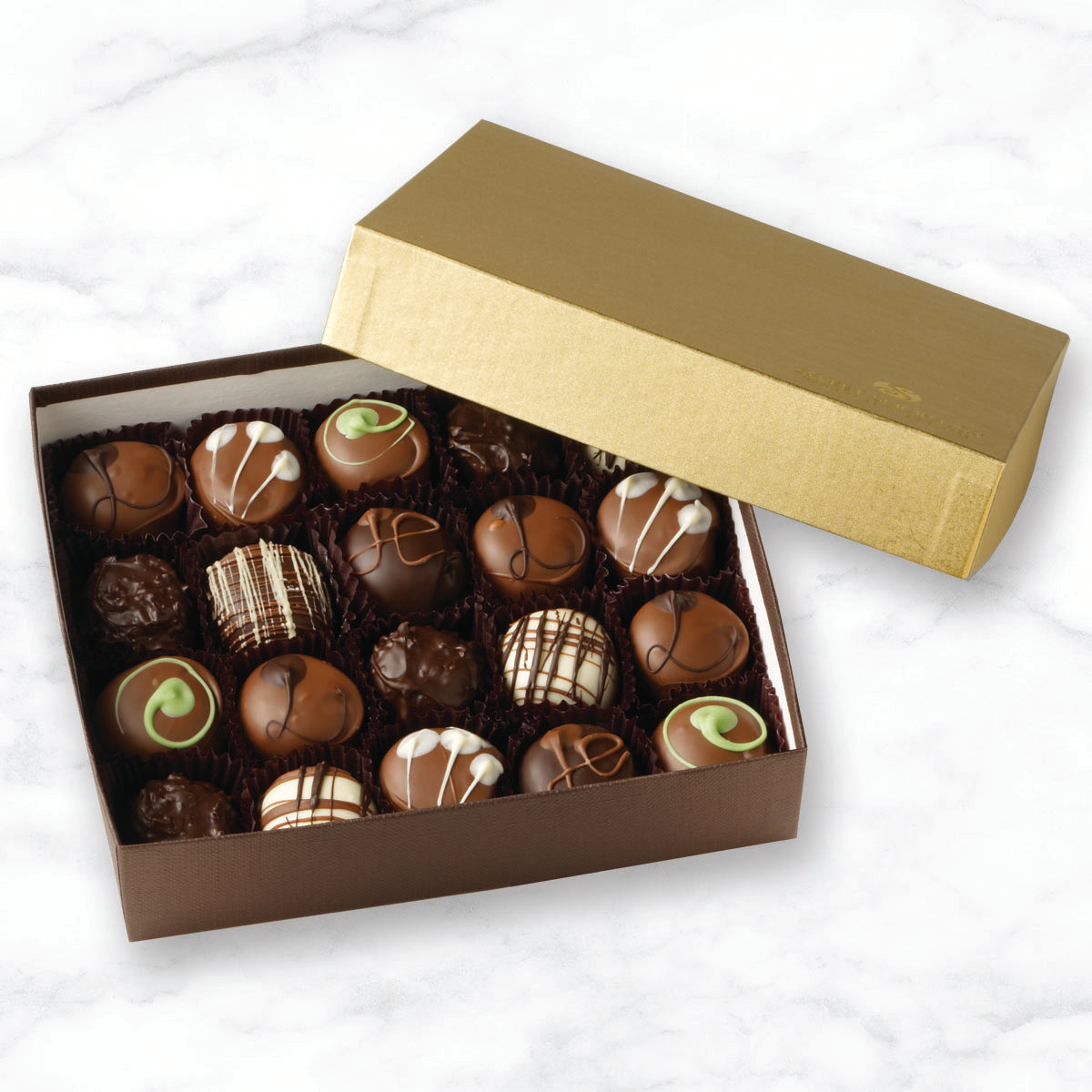 A box of assorted hand crafted chocolate truffles with a gold lid on a marble surface.