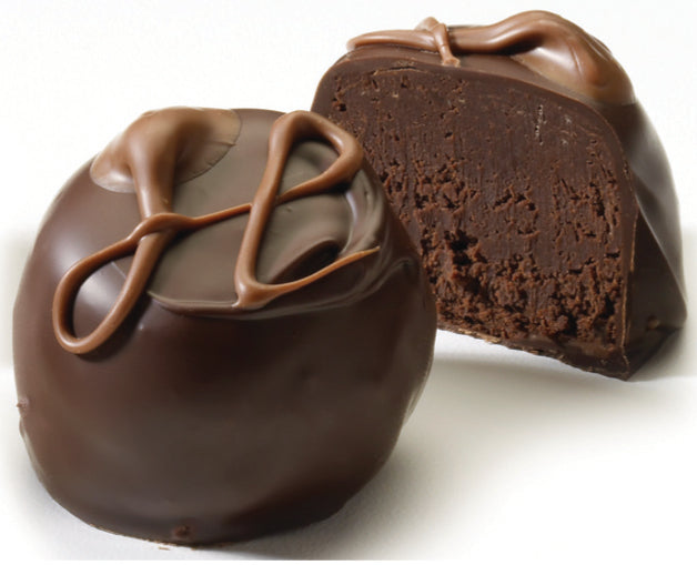 An image showing a whole and a half of a double chocolate truffle, with the half showing the rich dark chocolate center, drizzled with dark chocolate on top.